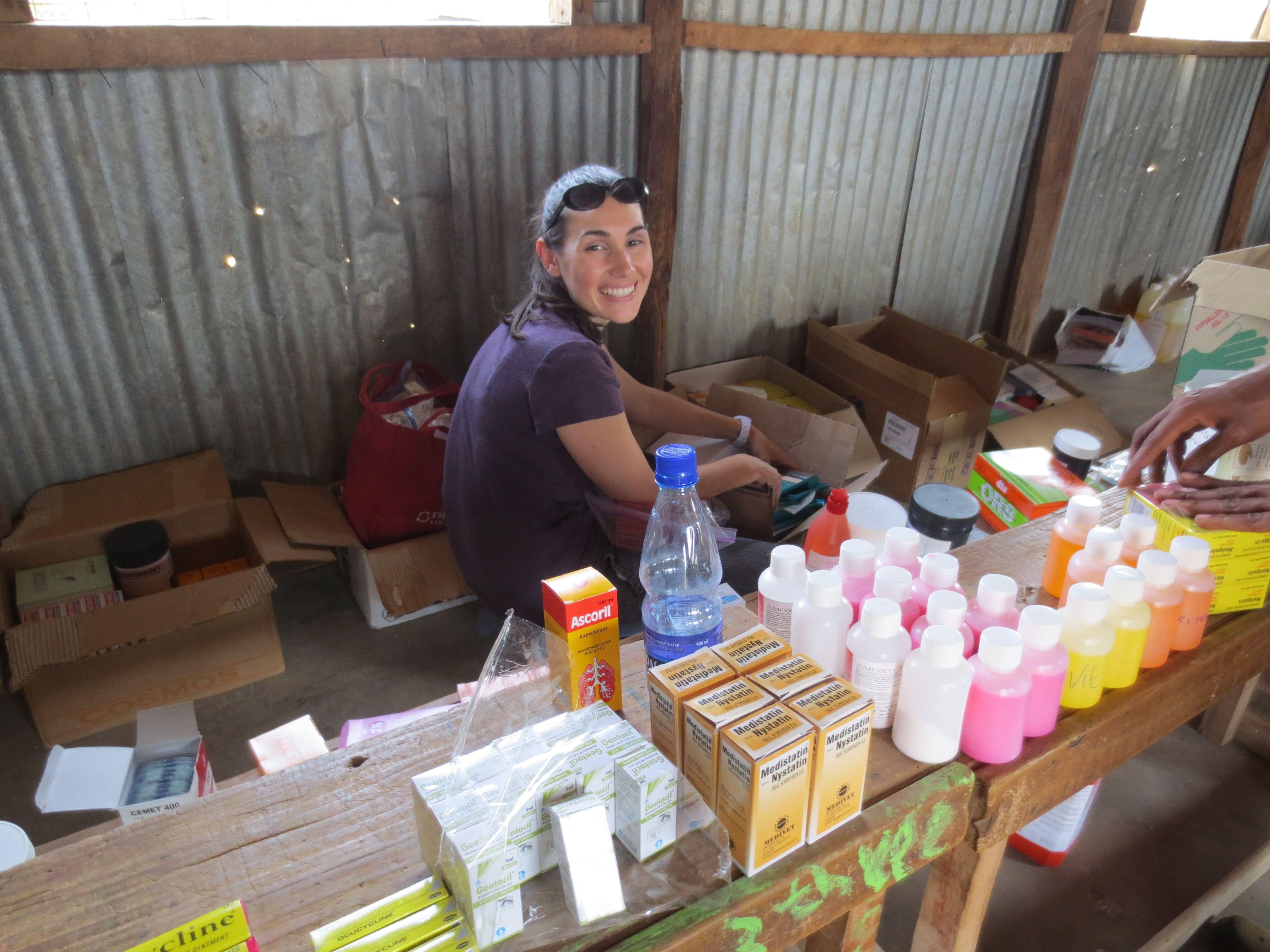 A Smiling Pharmacist with a Display of Medication